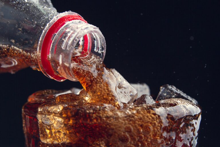 Botellas y latas de bebidas zero o sin azúcar sobre una mesa, con un fondo desenfocado.