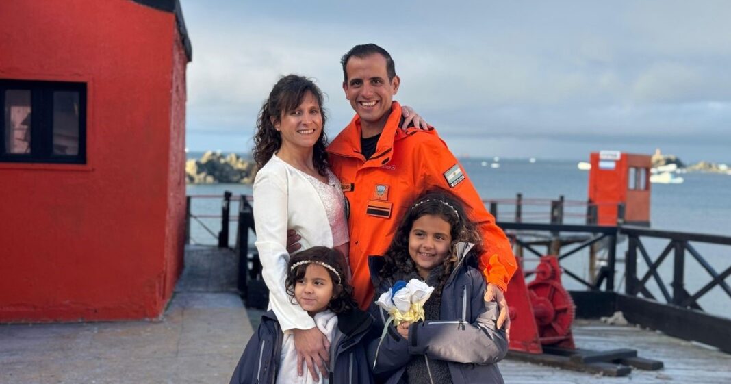 Familia posando frente a la Capilla Antártica San Francisco de Asís en Base Esperanza, Antártida.