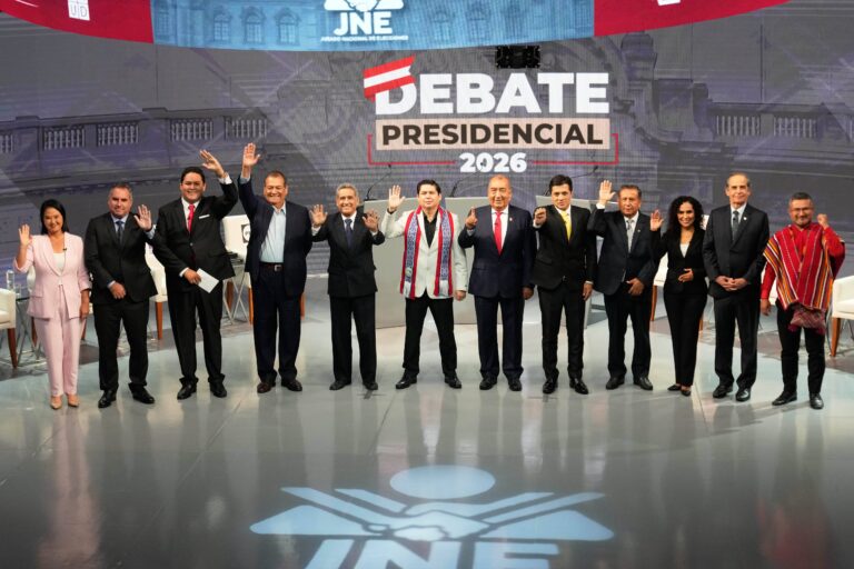 Persona consultando información electoral en un dispositivo móvil frente a la bandera de Perú.