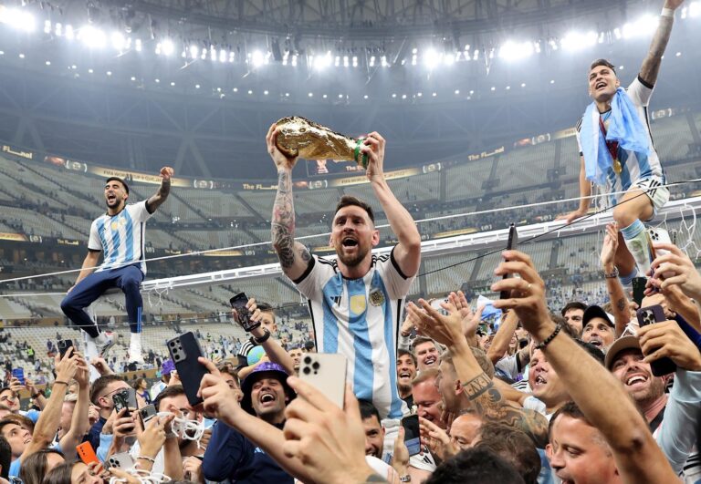 Grupo de personas conversando sobre fútbol con banderas argentinas de fondo, representando el análisis del clima previo al Mundial 2026.