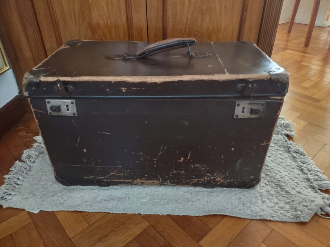 Baúl antiguo abierto con partituras musicales manuscritas en su interior.