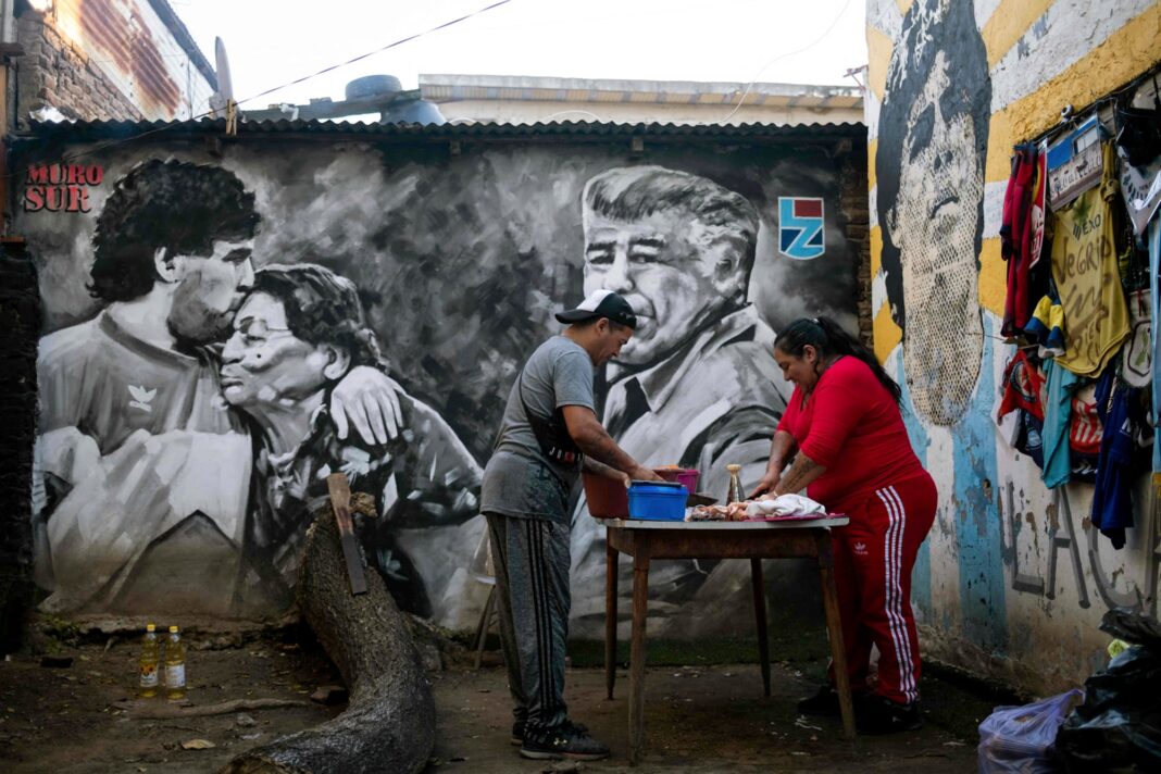 María Torres y un voluntario preparan comida en el comedor de la casa natal de Diego Maradona en Villa Fiorito.