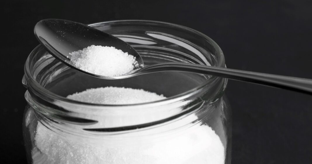 Persona aplicando bicarbonato de sodio en las guías de una ventana para limpiarlas