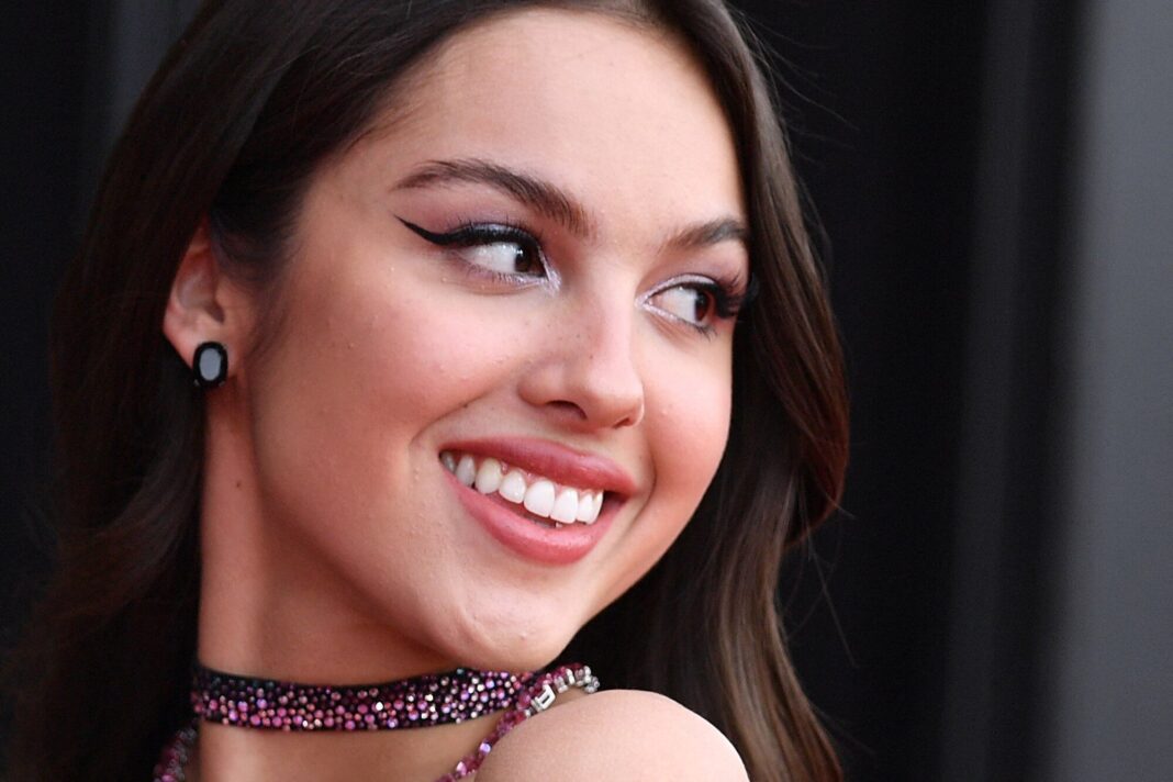 Olivia Rodrigo en la portada de su nuevo álbum, colgada de una hamaca con un vestido rosa y blanco.