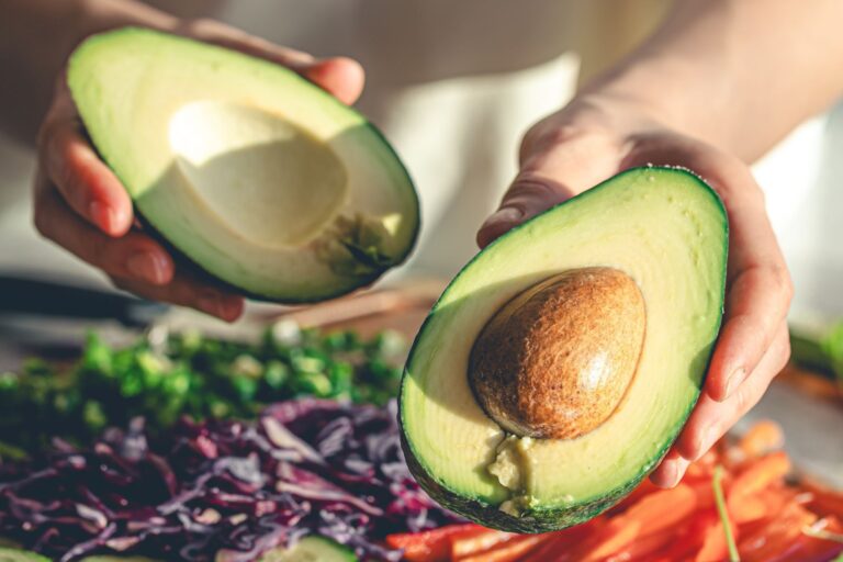 Mitades de una palta fresca sobre una tabla de madera.