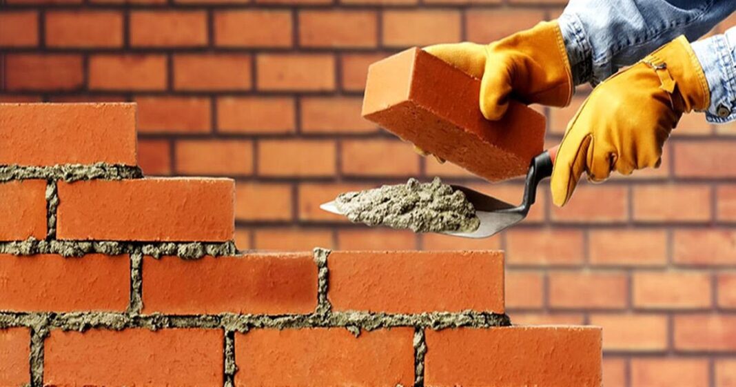 Obrero de la construcción trabajando en una obra, con herramientas y casco de seguridad.