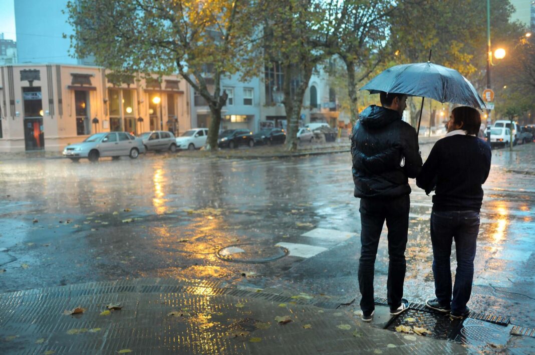 Calle anegada por la tormenta en el Área Metropolitana de Buenos Aires, con vehículos transitando lentamente.