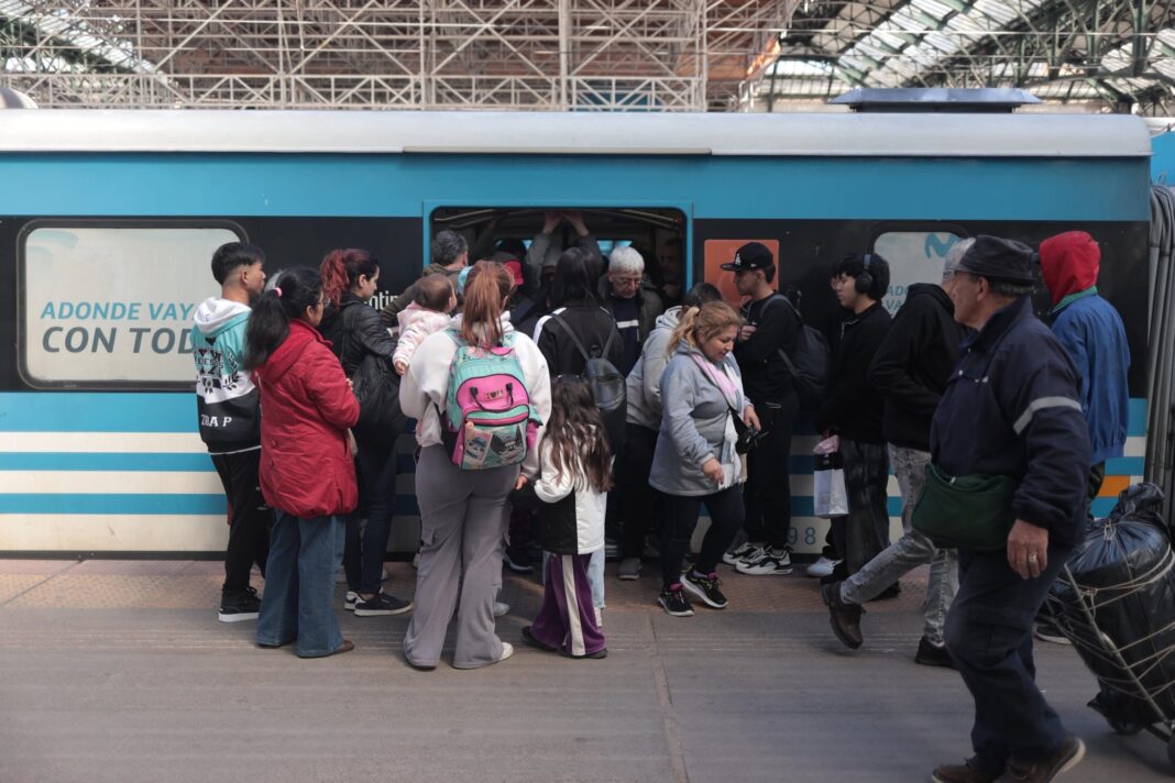 Personas esperando un colectivo en el AMBA con cartel de tarifas actualizadas