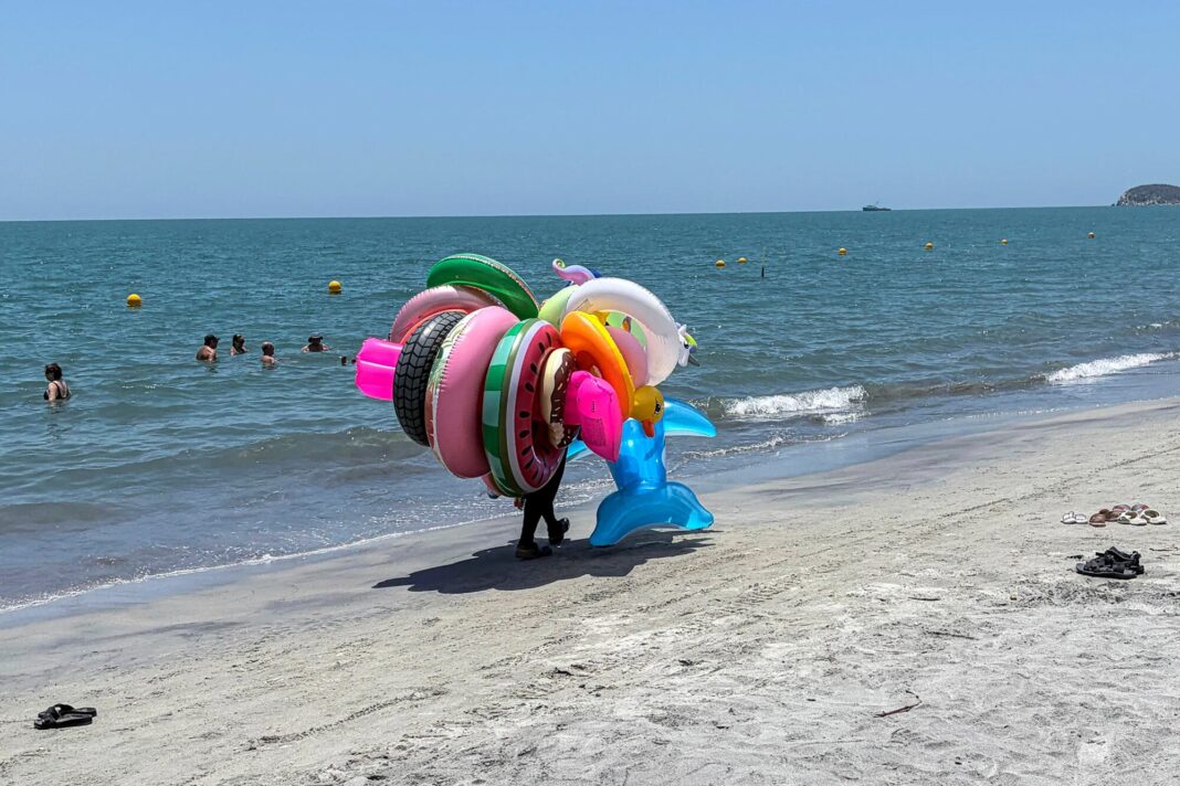 Playa soleada en Santa Marta con turistas y vendedor de inflables