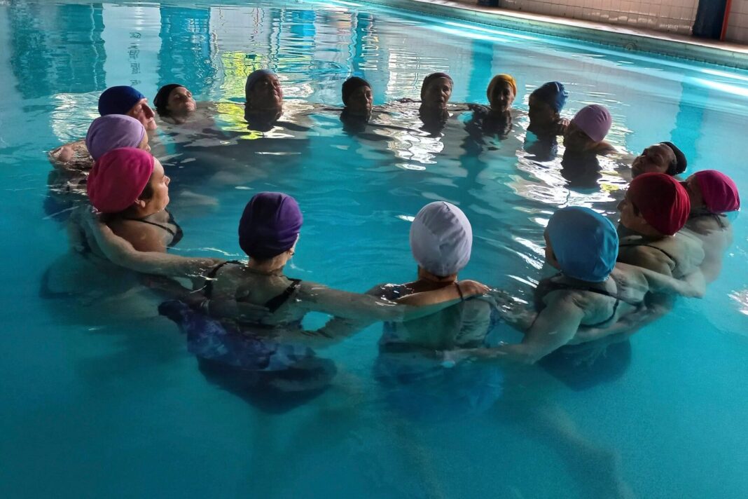 Personas realizando biodanza acuática en una piscina
