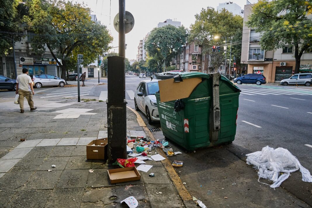 Contenedor de basura desbordado en una calle del barrio porteño de San Nicolás, con bolsas apiladas en la vereda