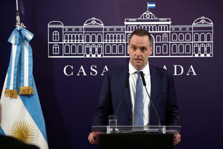 Sala de periodistas vacía en Casa Rosada con micrófonos y banderas argentinas