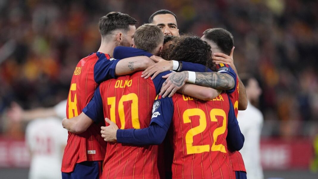 Balón de fútbol sobre césped con banderas de España y de países anfitriones del Mundial 2026