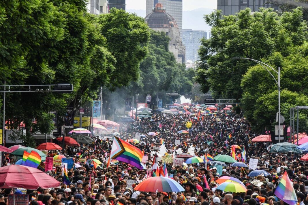 Personas marchando en la Marcha del Orgullo CDMX con banderas LGBTTTIQAP+