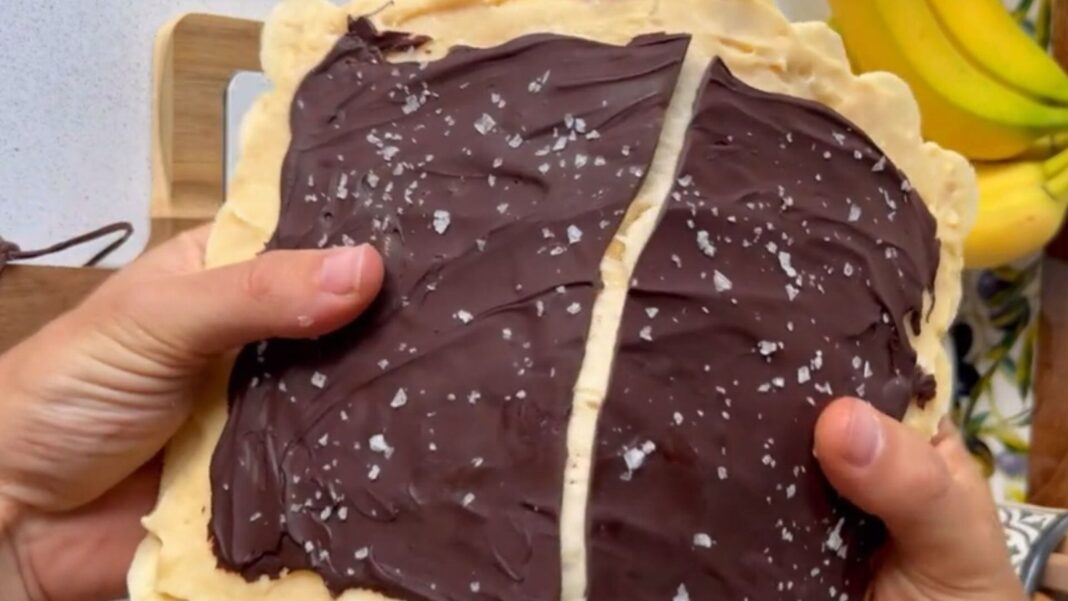Rodajas de plátano congeladas bañadas en chocolate negro sobre una bandeja con papel vegetal