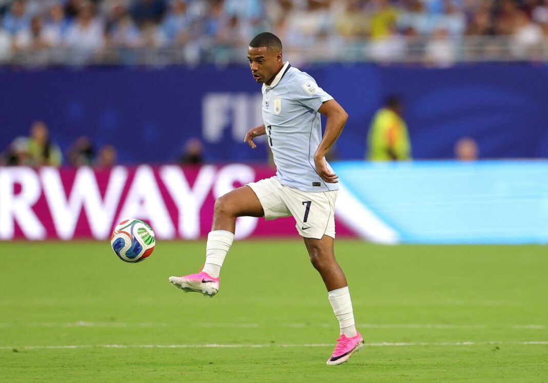 Escudos de Uruguay y Cabo Verde sobre fondo de estadio de fútbol
