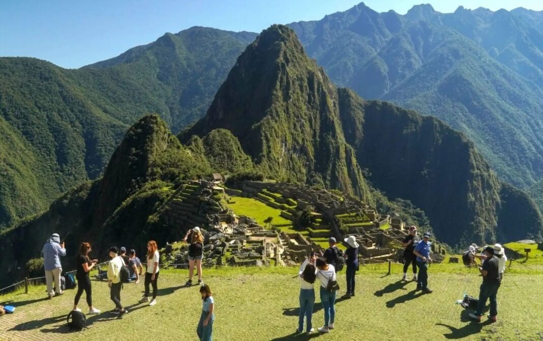 Vista de la ciudadela inca de Machu Picchu con turistas recorriendo sus terrazas