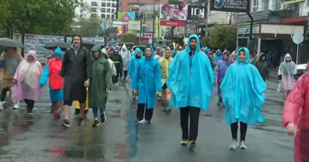 Peregrinos caminando bajo la lluvia hacia Luján